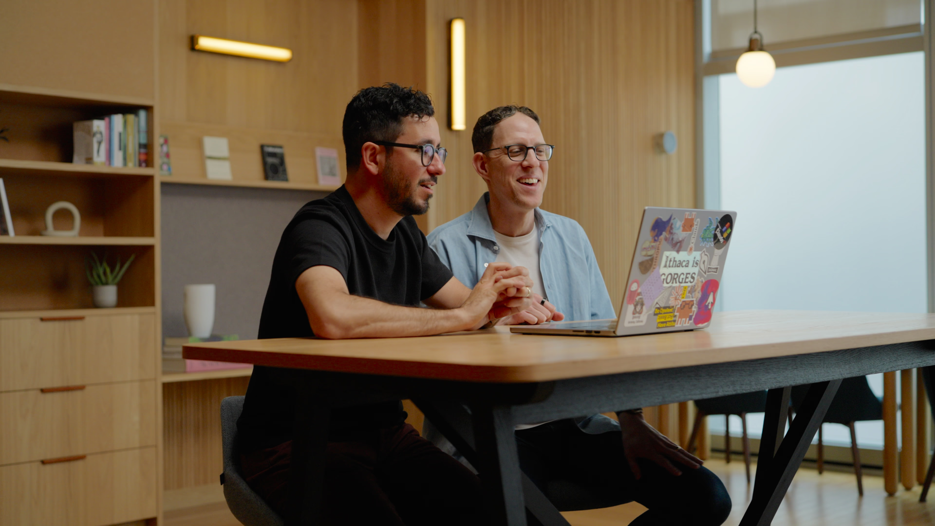 Two people connecting over a laptop in a warm, calm workspace
